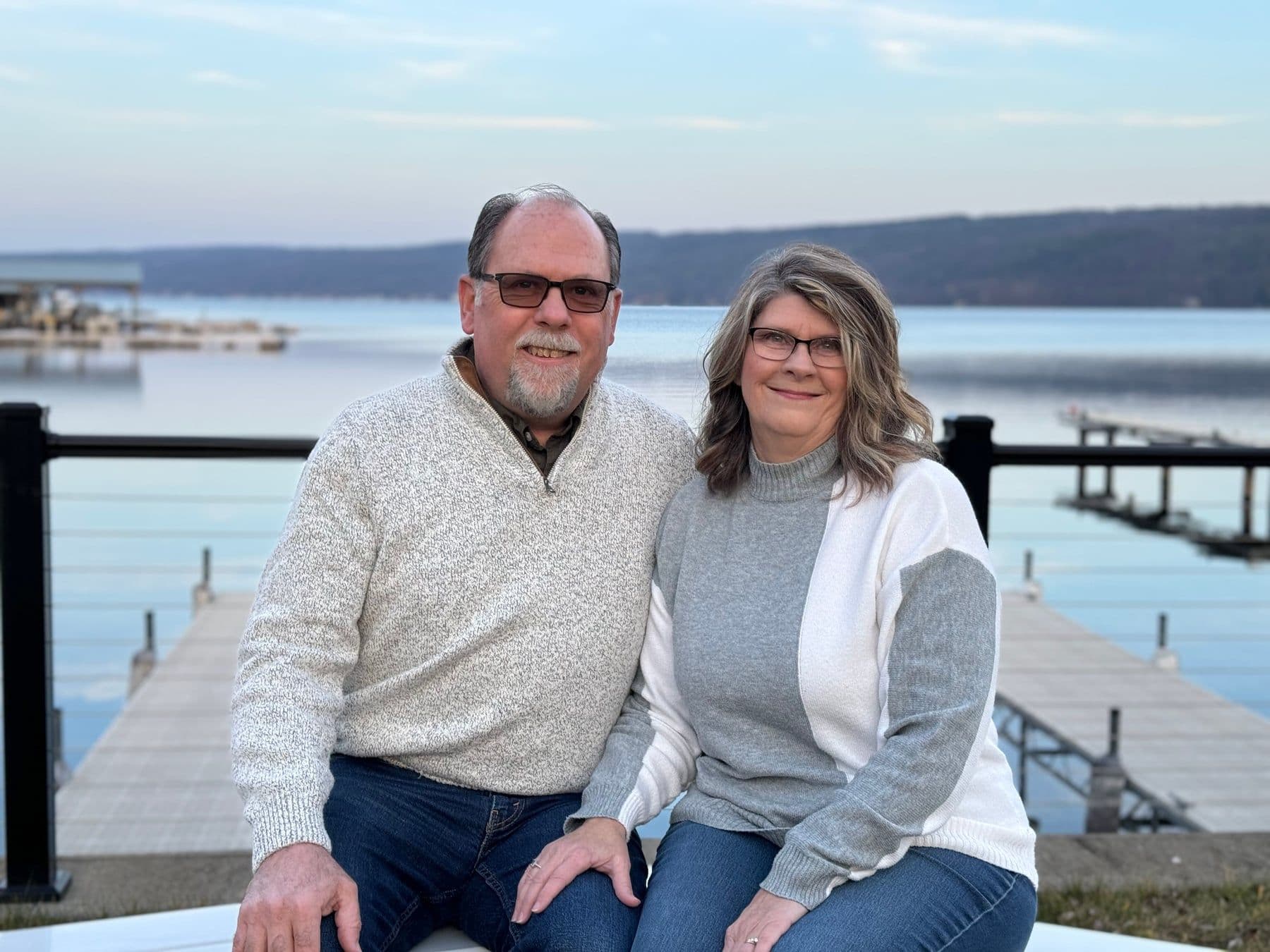 Ron and Deb Leonard, the innkeepers, sitting at the water's edge with the docks of Keuka Lake behind them