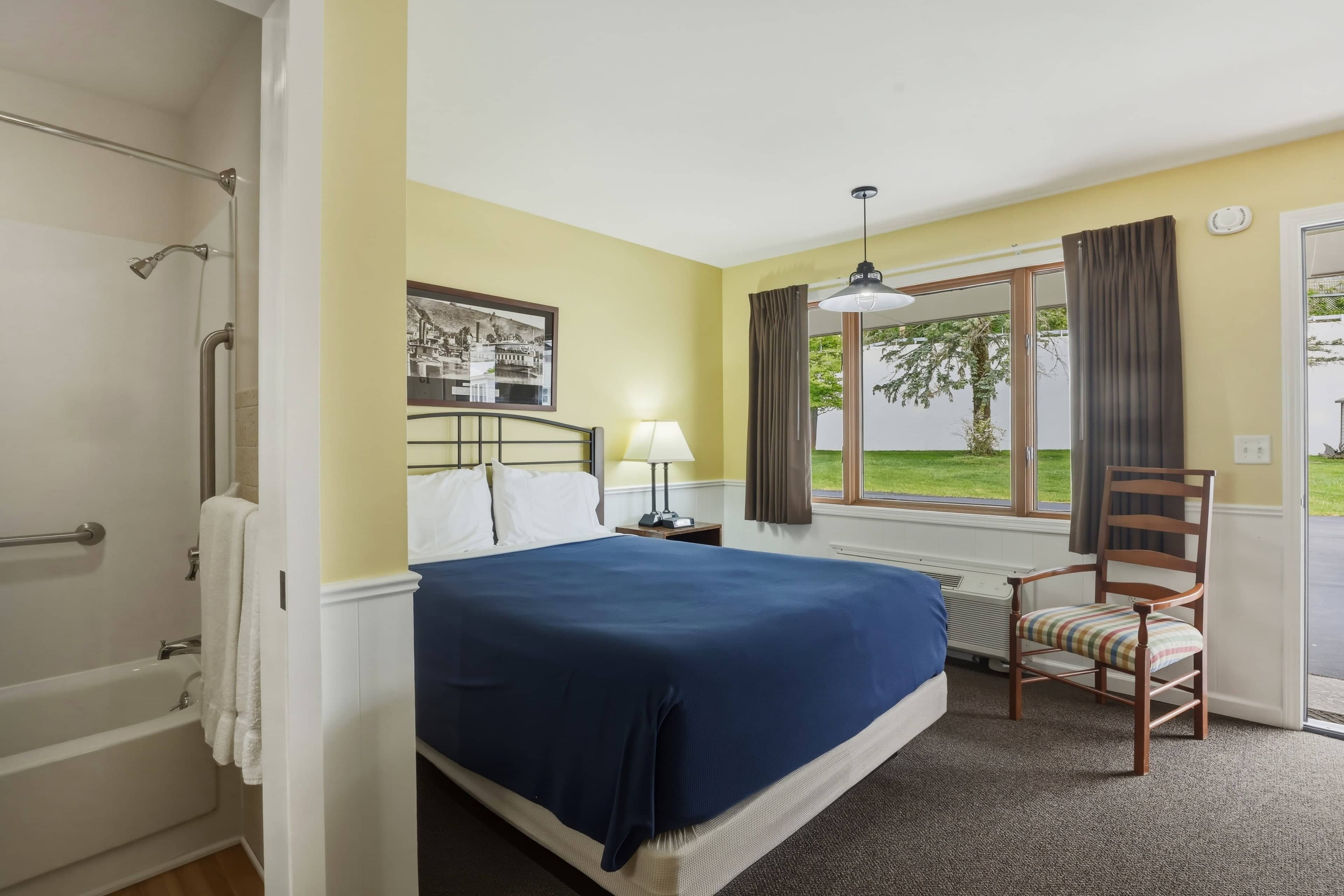 Single queen room — the queen bed, a window onto the lawn, and the bathroom beyond