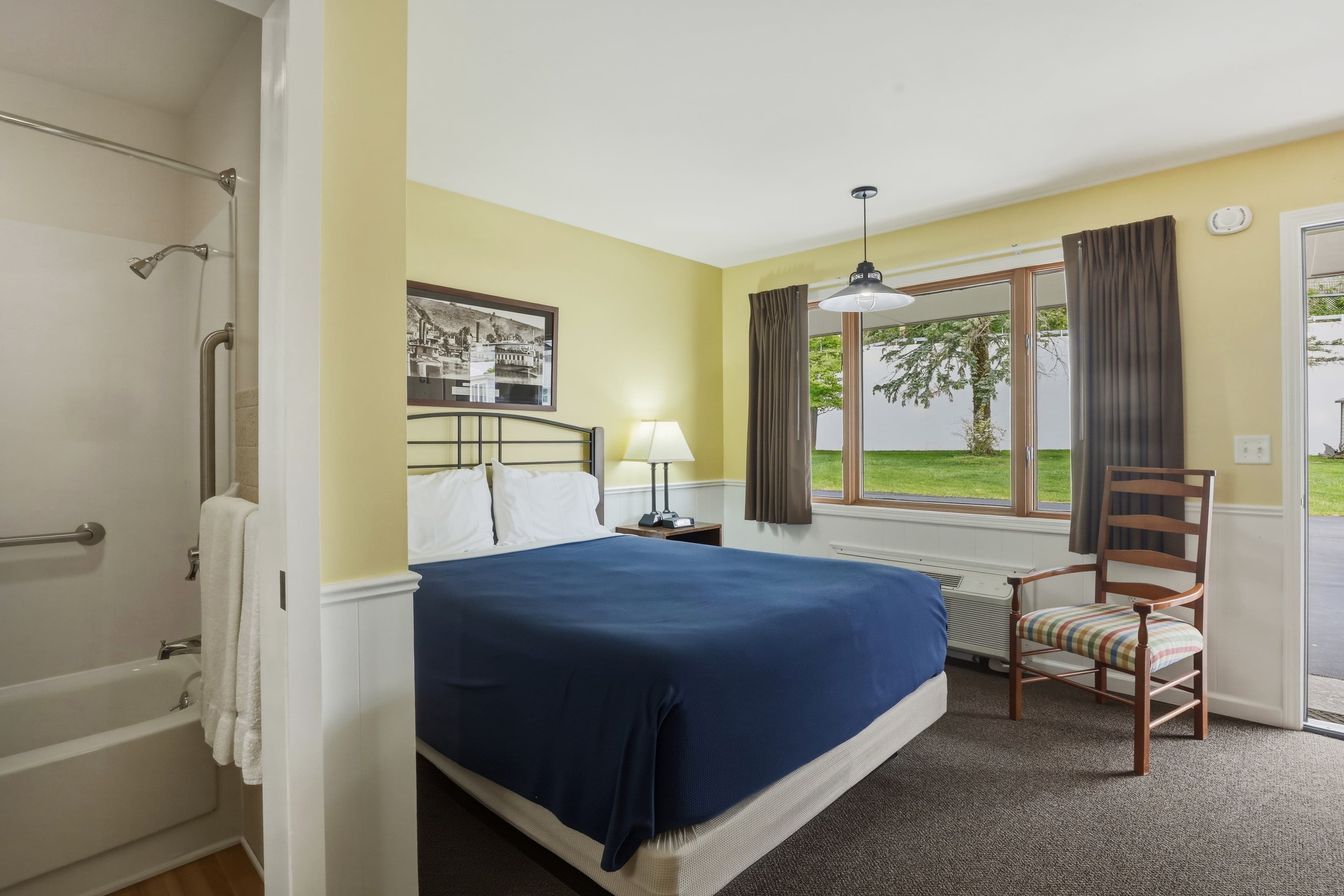 Single queen room — the queen bed, a window onto the lawn, and the bathroom beyond